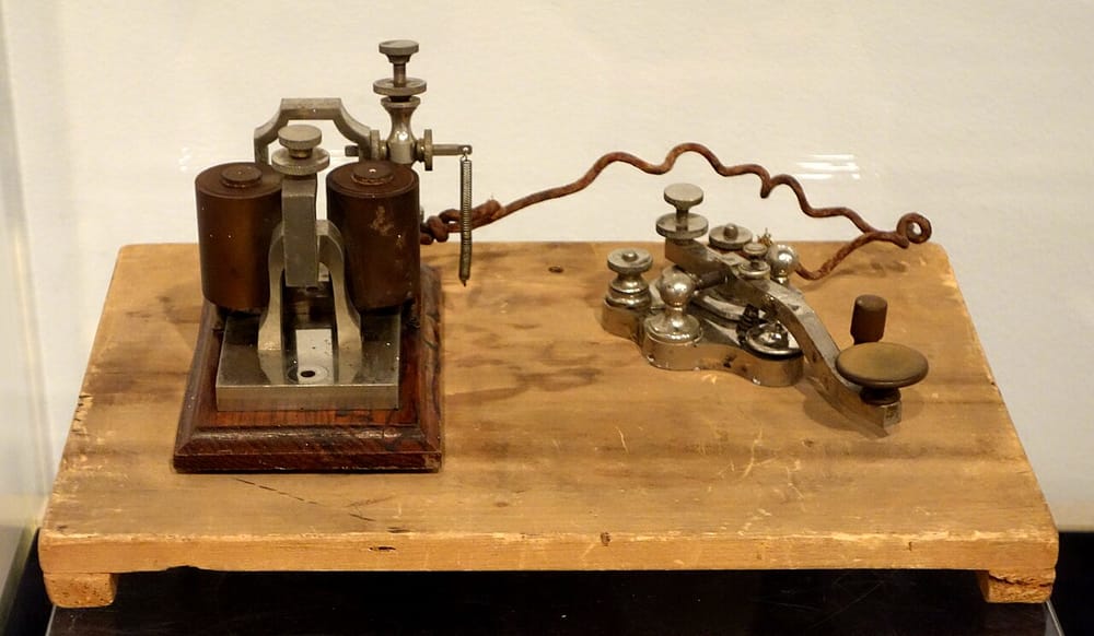 A telegraph set from about 1876. Left: the sounder, two coils of wire under a metal arm. Right: the key, a metal lever with a round knob.